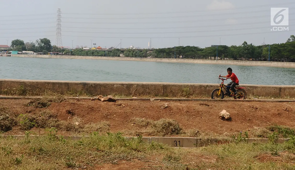 Seorang anak bermain sepeda di Waduk Cincin, Jakarta, Selasa (8/1). Pemerintah Kota Administratif Jakarta Utara berencana menata kawasan Hutan Kota Waduk Cincin yang berlokasi di kawasan Sunter, Jakarta Utara. (Liputan6.com/Herman Zakharia)