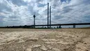 <p>Tanah kering di dasar sungai Rhine yang mengering sebagian terlihat di Duesseldorf, Jerman barat (25/7/2022). Keringnya sungah Rhine akibat Eropa mengalami gelombang panas. (AFP/Photo/Ina Fassbender)</p>
