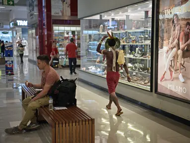 Anggota suku Kariri berjalan di sebuah mal di Brasilia (26/8/2021).  Ia masuk ke dalam mal saat para pengunjuk rasa suku pribumi lainnya berkumpul di ibu kota Brasil saat Mahkamah Agung bersiap untuk menangani kasus yang dapat menghilangkan keberatan di tanah leluhur mereka. (AFP/Carl De Souza)