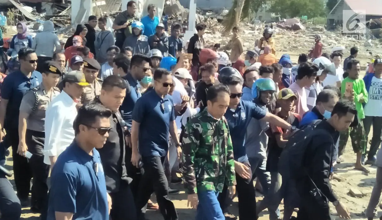 Presiden Joko Widodo (Jokowi) meninjau sejumlah titik yang terdampak bencana gempa dan tsunami di Kota Palu, Sulawesi Tengah, Minggu (30/9). Jokowi yang didampingi sejumlah jajarannya tampak mengenakan jaket loreng khas TNI. (Liputan6.com/Septian Deny)
