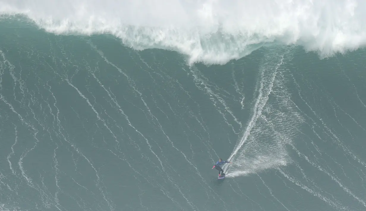 Peselancar Michelle des Bouillons dari Brasil mengendarai ombak selama kompetisi selancar ombak besar Nazare Tow Challenge di Praia do Norte, atau Pantai Utara, di Nazare, Portugal, Kamis, 10 Februari 2022. (AP Photo/Armando Franca)