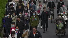 Orang-orang dan pengendara melintasi jalan pada jam sibuk malam hari di Beijing, China, Rabu (26/4/2023). (AP Photo/Andy Wong)