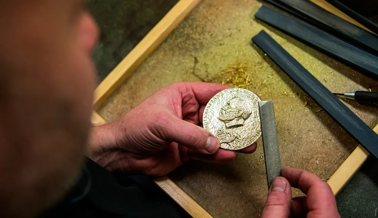 <p>Perajin Niklas Qvarnstrom menyelesaikan pembuatan medali hadiah Nobel di Eskilstuna, Swedia, 29 Oktober 2019. Niklas Qvarnstrom merupakan perajin yang bertanggung jawab atas medali hadiah Nobel. (Jonathan NACKSTRAND/AFP)</p>
