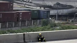 Petugas pemadam beristirahat di pinggir jalan dekat lokasi ledakan di pelabuhan Kota Tianjin, China, Kamis (13/8/2015). Ledakan yang diperkirakan berkekuatan setara 21 ton TNT ini menewaskan 17 orang dan ratusan lainya terluka. (REUTERS/Jason Lee)