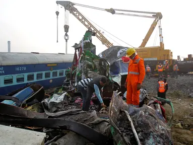Petugas penyelamat mencari korban di antara bangkai kereta api setelah terjadi kecelakaan di Pukhrayan, Kanpur, India (21/11). Kebanyakan korban terjebak karena masih tertidur saat kereta mengalami kecelakaan pada pagi hari. (Reuters/ Jitendra Prakash)