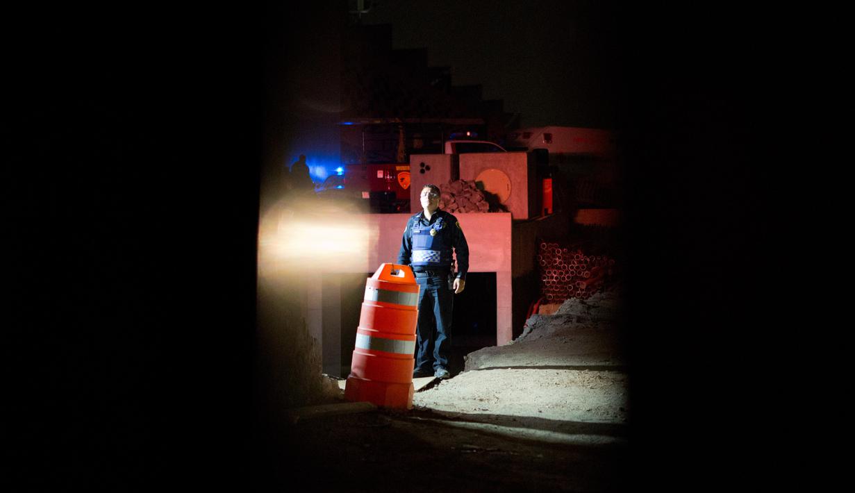 Petugas keamanan berdiri di dekat bangunan garasi parkir bawah tanah yang runtuh di sebuah kompleks di Mexico City (10/4). Untuk mengevakuasi korban, petugas mengerahkan anjing penyelamat. (AP Photo/Rebecca Blackwell)