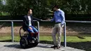 Pencipta MarioWay, Mario Vigentini (kiri) menjajal temuannya di Taman Ilmiah dan Teknologi "Kilometro Rosso", Italia, 19 Juli 2017. Kursi roda listrik itu mampu membuat mereka yang mendudukinya sejajar dengan tinggi orang yang berdiri. (MIGUEL MEDINA/AFP)