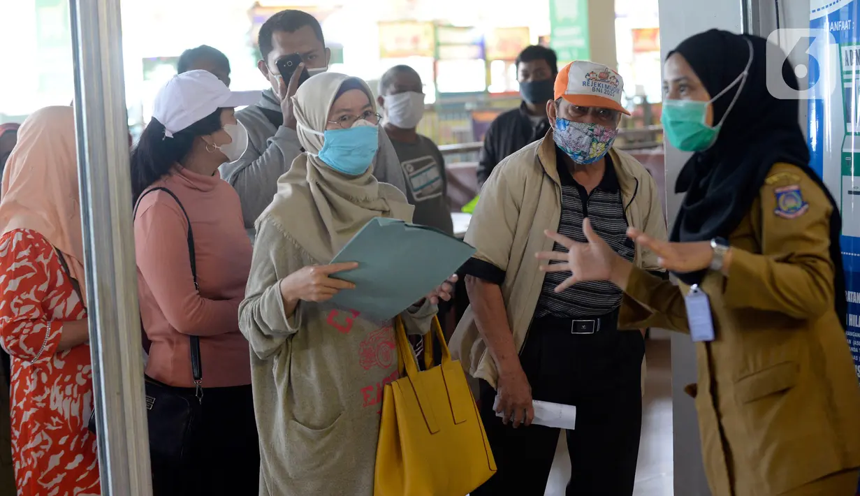 Petugas memberikan penjelasan kepada warga yang akan melakukan pencetakan di mesin Anjungan Dukcapil Mandiri (ADM) di Pamulang Square, Tangerang Selatan, Senin (15/9/2020). Warga dapat melakukan pelayanan kependudukan tanpa perlu lagi datang ke kantor Disdukcapil di ADM. (merdeka.com/Dwi Narwoko)
