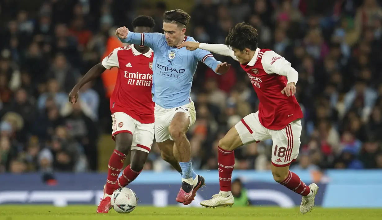 <p>Gelandang Jack Grealish dari Manchester City berusaha melewati dua pemain Arsenal selama pertandingan putaran ke-4 Piala FA di Stadion Etihad di Manchester, Inggris, Sabtu (28/1/2023). Hasil ini membawa Manchester City lolos ke putaran kelima Piala FA 2022-2023. (AP Photo/Dave Thompson)</p>
