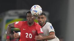 Penyerang Maroko, Abderrazak Hamdallah berebut bola dengan pemain Kanada, Jonathan David selama pertandingan grup F Piala Dunia 2022 di Stadion Al Thumama di Doha, Qatar, Kamis (1/12/2022). Maroko menang tipis atas Kanada dengan skor 2-1. (AP Photo/Frank Augstein)