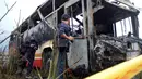 Petugas menginvestigasi bus pariwisata berisi wisatawan dari China daratan yang terbakar di dekat ibu kota Taiwan, Selasa (19/7). Bus yang dalam perjalanan ke bandara itu menabrak pagar jalan raya dan terbakar hingga menewaskan 26 orang. (Sam YEH/AFP)