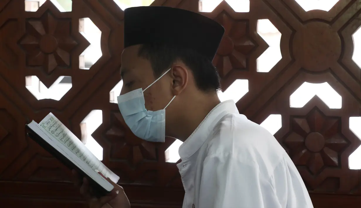 Seorang siswa mengenakan masker untuk membantu mengekang penyebaran COVID-19 saat membaca kitab suci Alquran di Masjid Attaqwa, Bekasi, Jawa Barat, Selasa (4/5/2021). Selama Ramadhan, umat muslim menahan diri dari makan, minum, merokok dan seks dari subuh hingga maghrib. (AP Photo/Achmad Ibrahim)