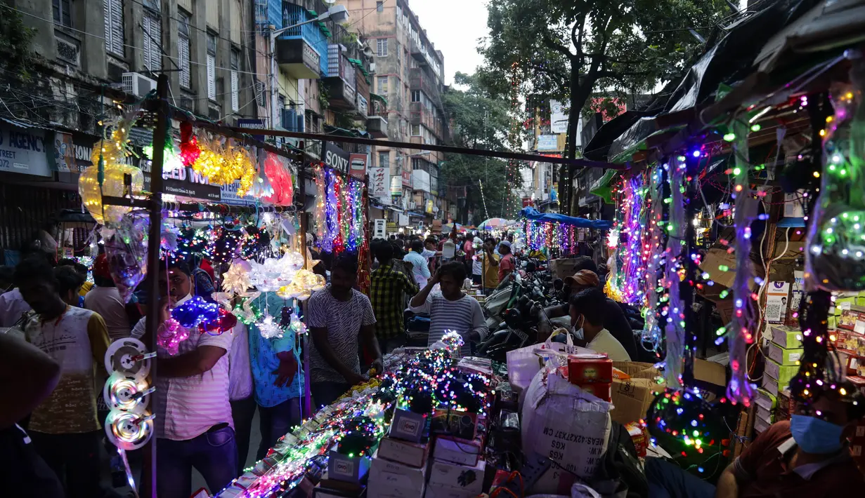 Pelanggan berjalan melewati deretan kios yang menjual lampu hias menjelang Diwali, festival lampu Hindu, di Kolkata, India, Rabu (27/10/2021). Diwali adalah salah satu festival paling penting dalam agama Hindu, yang didedikasikan untuk ibadah Dewi Laksmi. (AP Photo/Bikas Das)