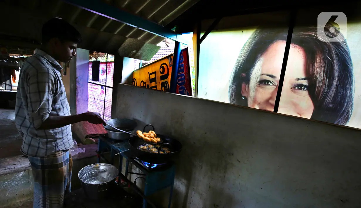 Pekerja menyiapkan camilan tradisional di sebelah spanduk yang menampilkan Wakil Presiden AS terpilih Kamala Harris di luar restoran lokal di Thulasendrapuram, selatan Chennai, Tamil Nadu, India, Rabu (20/1/2021). (AP Photo/Aijaz Rahi)