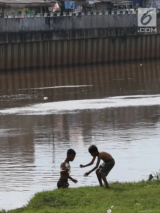 Anak-anak usai bermain sepak bola di bantaran Kanal Banjir Barat, Jakarta, Jumat (5/4). Tidak adanya lapangan menjadikan lokasi tersebut sebagai tempat bermain mereka, meskipun dalam kondisi seadanya. (Liputan6.com/Immanuel Antonius)