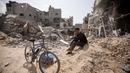 Seorang warga Palestina duduk di antara puing-puing bangunan yang hancur setelah pasukan Israel meninggalkan Khan Younis, Jalur Gaza, Rabu, 6 Maret 2024. (AP Photo/Mohammed Dahman)