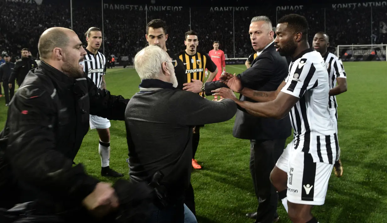 Presiden PAOK Ivan Savvidis turun ke lapangan dengan pistol di pinggangnya saat Liga Super Yunani di Stadion Toumbas, Minggu (11/3). Savvidis memprotes wasit yang membatalkan gol PAOK yang dicetak Fernando Valera pada menit ke-89. (AFP PHOTO/stringer)