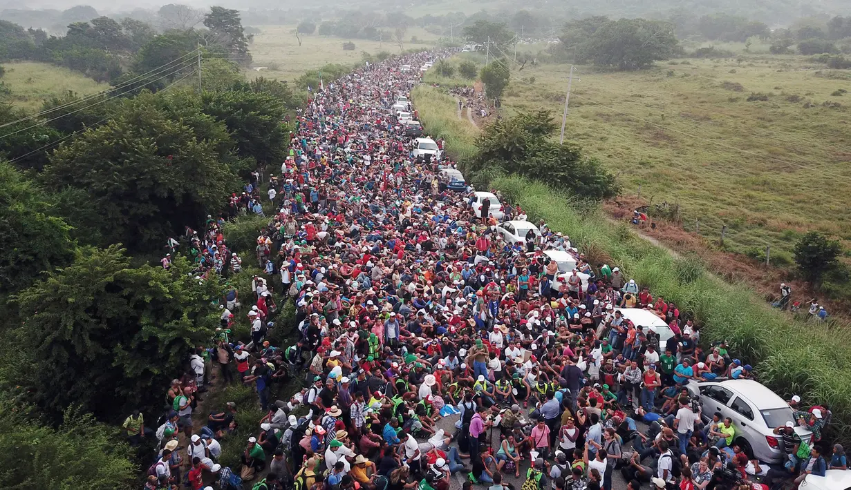 Rombongan imigran Amerika Tengah tujuan Amerika Serikat berkumpul di jalan raya setelah polisi federal memblokir jalan mereka di luar Kota Arriaga, Meksiko, Sabtu (27/10). Pemerintah Meksiko menghalangi rombongan menuju AS. (AP Photo/Rodrigo Abd)