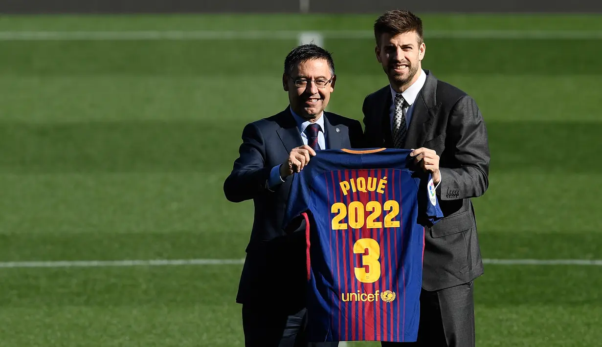 Bek Spanyol, Gerard Pique dan Presiden Barcelona FC, Josep Maria  berpose memegang jersey Barcelona pada pengumuman perpanjangan kontraknya di stadion Camp Nou, Senin (29/1). Pique memperpanjang kontraknya bersama Barcelona hingga 2022. (LLUIS GENE/AFP)