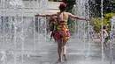 Seorang wanita menyegarkan dirinya di air mancur taman Andre Citroen, Paris, Senin (19/6). Suhu temperatur di ibu kota Prancis ini mencapai 36 derajat celcius. (AFP Photo / LUDOVIC MARIN)