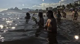 Pemuja dewi laut Yemanja menempatkan persembahan bunga  di perairan pantai Arpoador selama perayaan tahunan di Rio de Janeiro, Brasil, Kamis, 2 Februari 2023. Dalam kepercayaan Afro-Brasil, Yemanja diyakini sebagai representasi dewi laut yang cantik jelita. (AP Photo/Bruna Prado)