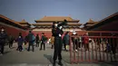 Seorang penjaga keamanan menggunakan pengeras suara untuk menyarankan wisatawan untuk memindai kode kesehatan mereka sebelum memasuki Kota Terlarang di Beijing (25/10/2020). (AP Photo/Andy Wong)