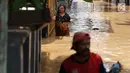 Warga melintasi banjir yang menggenangi kawasan Pejaten Timur, Jakarta, Jumat (26/4). Banjir yang berasal dari luapan Sungai Ciliwung tersebut merendam ratusan rumah warga hingga kedalaman lebih dari satu meter. (Liputan6.com/Immanuel Antonius)