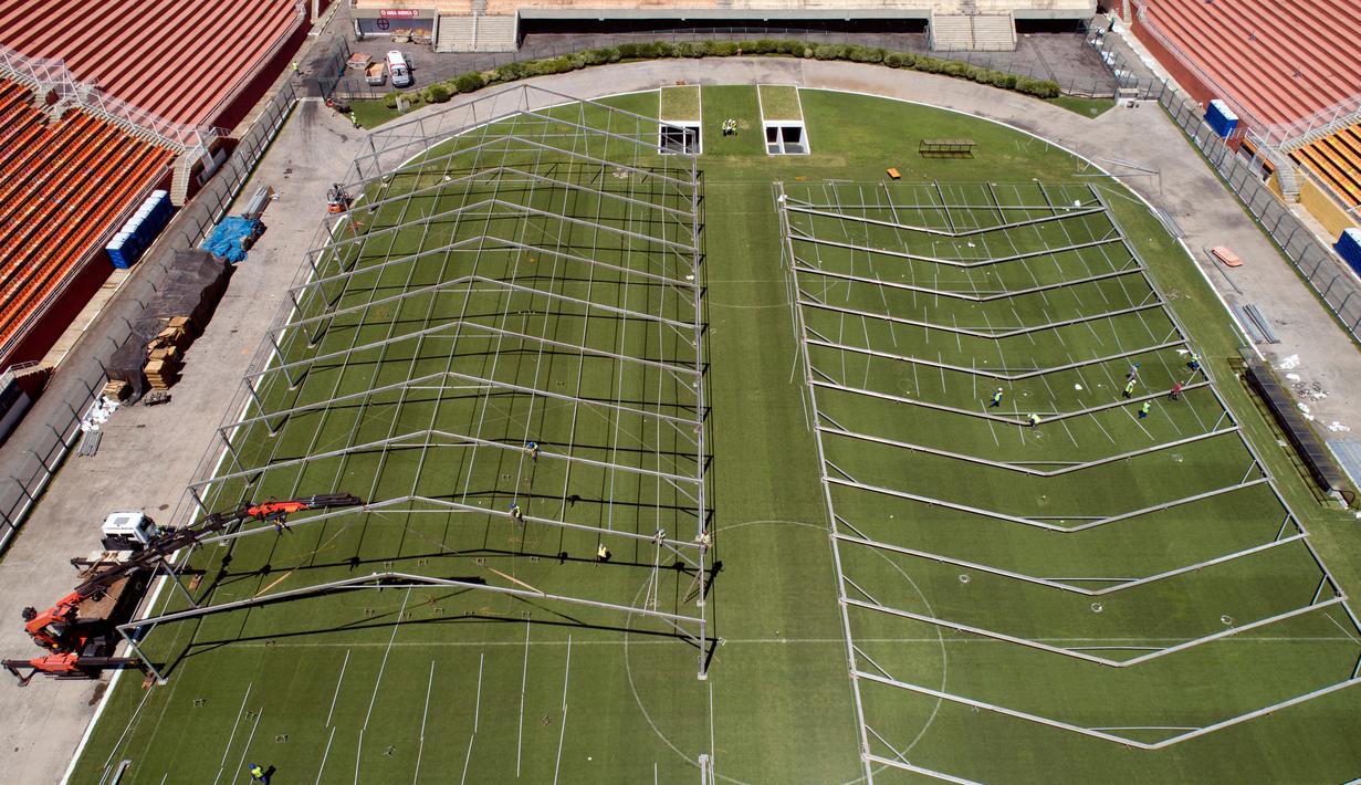 Pekerja membangun rumah sakit darurat bagi pasien terinfeksi Covid-19 di lapangan stadion Pacaembu, di Sao Paulo, Senin (23/3/2020). Sejumlah klub sepakbola papan atas Brasil meminjamkan stadion ke otoritas setempat untuk diubah menjadi rumah sakit atau klinik darurat virus corona. (AP/Andre Penner)
