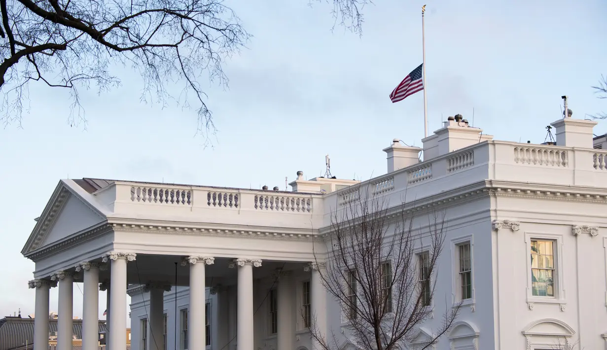 Bendera Amerika tampak berkibar setengah tiang untuk menandai 500.000 kematian akibat Covid-19 di Gedung Putih di Washington D.C. pada Senin (22/2/2021). Presiden Joe Biden memerintahkan agar bendera AS di properti federal diturunkan menjadi setengah tiang selama lima hari. (SAUL LOEB/AFP)