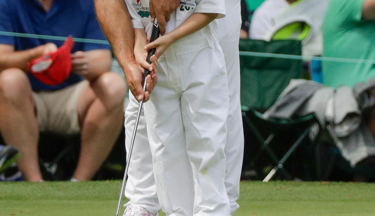 Pegolf dari Italia, Francesco Molinari membantu putranya, Tomasso memukul bola ketika hari terakhir mengikuti latihan untuk turnamen golf Masters 2018 di Augusta, Georgia, Rabu (4/4). (AP Photo/Matt Slocum)