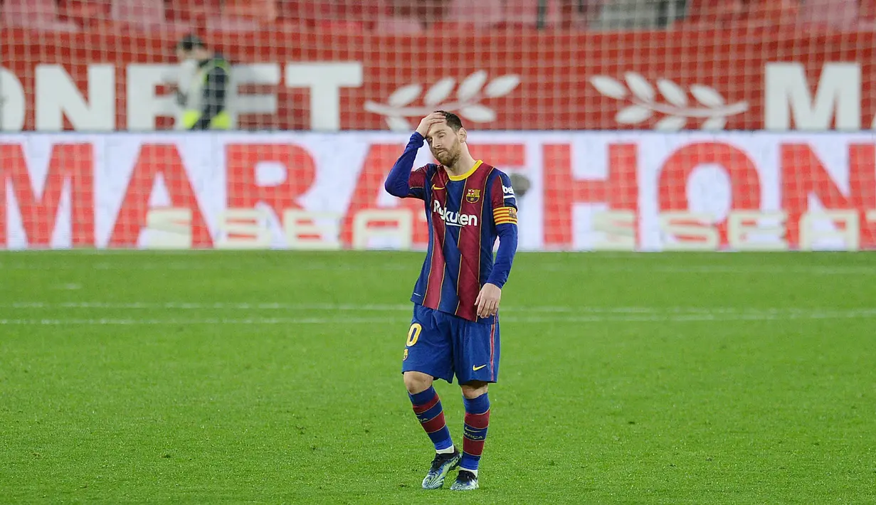 Striker Barcelona, Lionel Messi, memegang kepalanya usai ditaklukkan Sevilla pada laga leg pertama semifinal Copa del Rey di Estadio Ramon Sanchez Pizjuan, Kamis (11/2/2021). Barcelona tumbang dengan skor 2-0. (AFP/Cristina Quicler)
