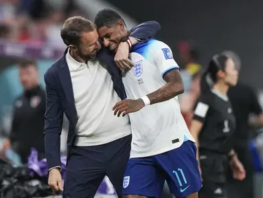 Pelatih Inggris, Gareth Southgate memeluk pemainnya, Marcus Rashford saat matchday ketiga Piala Dunia 2022 melawan Wales di Ahmad Bin Ali Stadium, Rabu (30/11/2022). (AP/Frank Augstein)