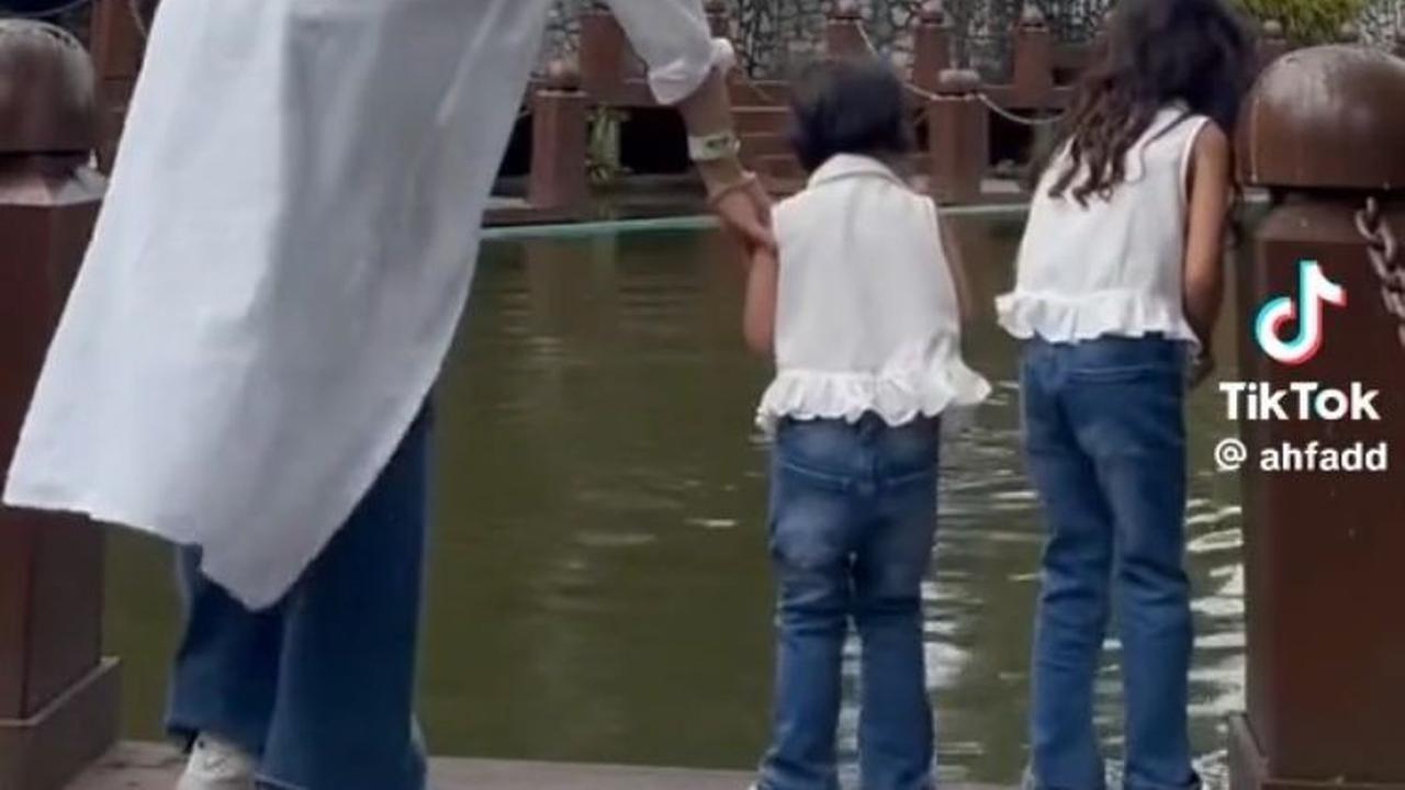 Menemani dua anak balitanya memberi makan ikan di tepi kolam, wanita ini tampak menjaga keduanya. Namun, sang adik yang tampak lebih aktif mencuri perhatian ibunya sehingga sang ibu lebih fokus menjaga anak keduanya.