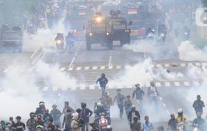 Petugas Brimob Polri menembakkan gas air mata untuk membubarkan massa usai terjadi lemparan batu di Jalan MH Thamrin, Jakarta, Selas (13/10/2020). Massa pengunjuk rasa yang menolak Omnibus Law akhirnya dibubarkan aparat. (merdeka.com/Arie Basuki)