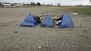 Tenda didirikan di kamp darurat di luar Calais, Sabtu (277/11/2021). Di kamp-kamp darurat di luar Calais, para migran menunggu kesempatan menyeberangi Selat Inggris meskipun minggu ini sekitar 27 orang tewas saat perahu mereka tenggelam beberapa mil dari pantai Prancis. (AP Photo/Rafael Yaghobzadeh)