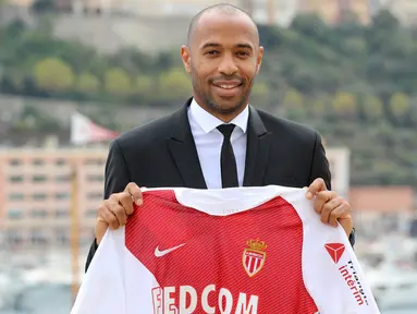 Legenda Prancis, Thierry Henry, memegang jersey saat diperkenalkan sebagai pelatih baru AS Monaco di Monaco, Rabu (17/10). Dirinya menggantikan posisi yang ditinggalkan Leonardo Jardim. (AFP/Valery Hache)