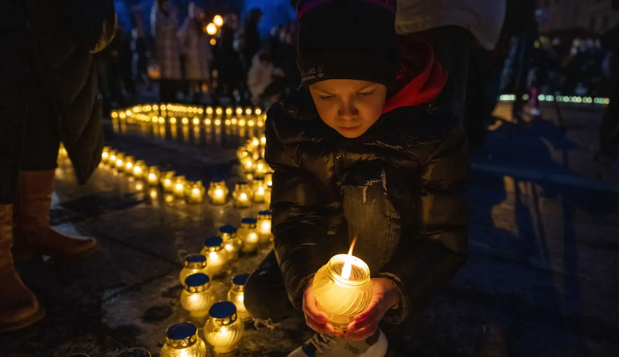 Orang-orang menyalakan lilin membentuk peta Ukraina, untuk mengenang nyawa yang hilang, di depan monumen Taras Shevchenko, di Lviv, Ukraina barat, Selasa malam (5/4/2022). Warga Ukraina berkumpul untuk momen menghormati nyawa yang hilang dalam perang. (AP Photo/Nariman El- Mofty)