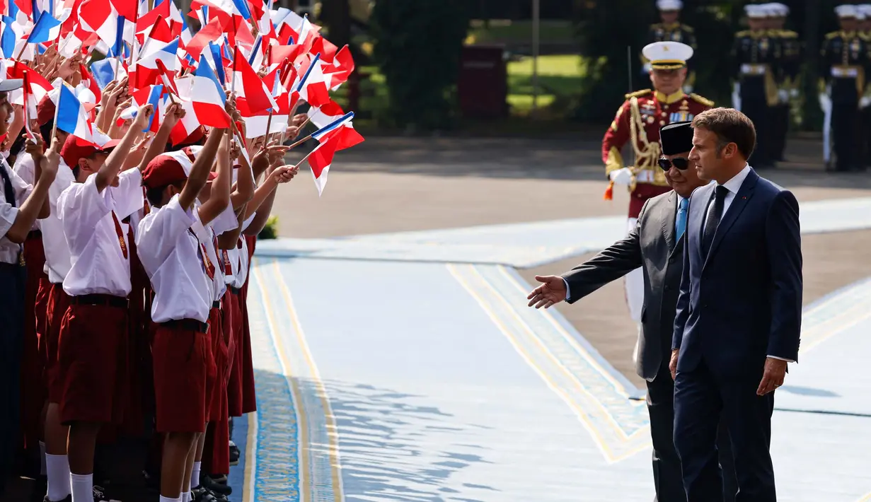 Presiden Republik Indonesia Prabowo Subianto (kedua kanan) bersama Presiden Prancis Emmanuel Macron melihat anak-anak sekolah yang mengibarkan bendera kedua negara dalam rangkaian upacara penyambutan di Istana Merdeka, Jakarta, Rabu 28 Mei 2025. (Ludovic MARIN/AFP)