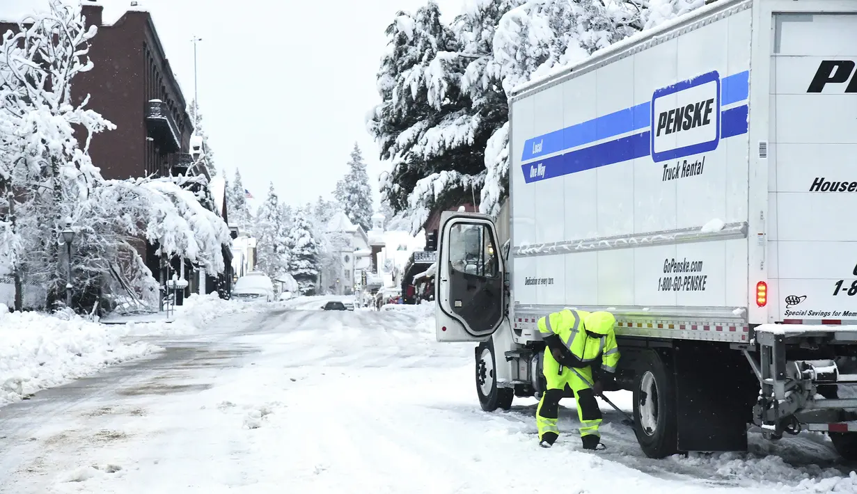 Seorang pengemudi truk Penske menunggu kedatangan rantai ban pada Senin pagi di sepanjang jalan layang Broad Street, di Nevada City, California (27/12/2021). Banyak warga yang tidak mendapatkan listrik atau terjebak di salju. (Elias Funez/The Union via AP)