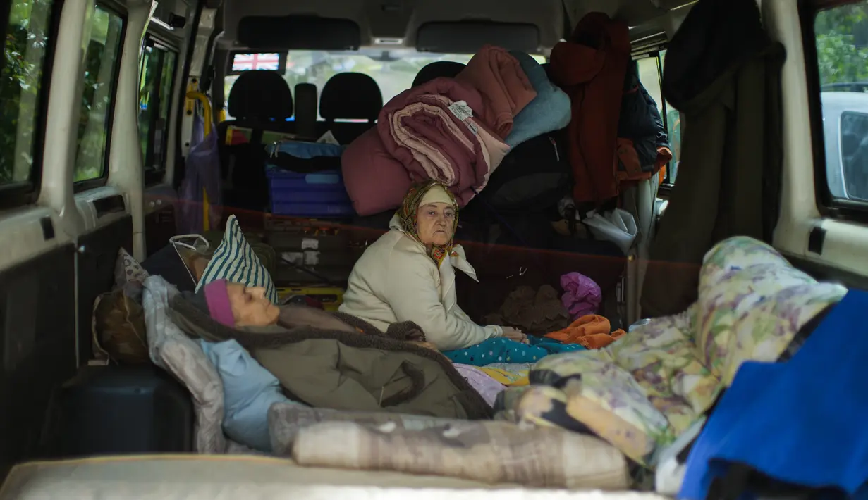 <p>Dua perempuan duduk di dalam sebuah van saat mereka dievakuasi di Bakhmut, Ukraina timur, Selasa (24/5/2022). Kota Bakhmut telah mengalami peningkatan serangan artileri, terutama selama seminggu terakhir, ketika pasukan Rusia mencoba untuk terus maju mengepung kota Sieverodonetsk di timur laut. (AP Photo/Francisco Seco)</p>