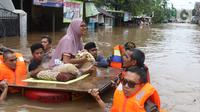 Petugas membantu mengevakuasi warga yang terjebak banjir di perumahan Ciledug Indah, Tangerang, Rabu (1/1/2020). Banjir setinggi dada orang dewasa terjadi akibat meluapnya kali angke. (Liputan6.com/Angga Yuniar)