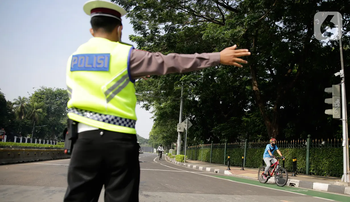 Petugas gabungan mengarahkan pengguna sepeda saat pengalihan jalur pesepeda di kawasan Sudirman-Thamrin, Jakarta, Minggu (5/9/2021). Pemberlakuan jalur ganjil genap pada masa PPKM membuat pengguna sepeda dilarang melintasi kawasan ganjil-genap pagi ini. (Liputan6.com/Angga Yuniar)