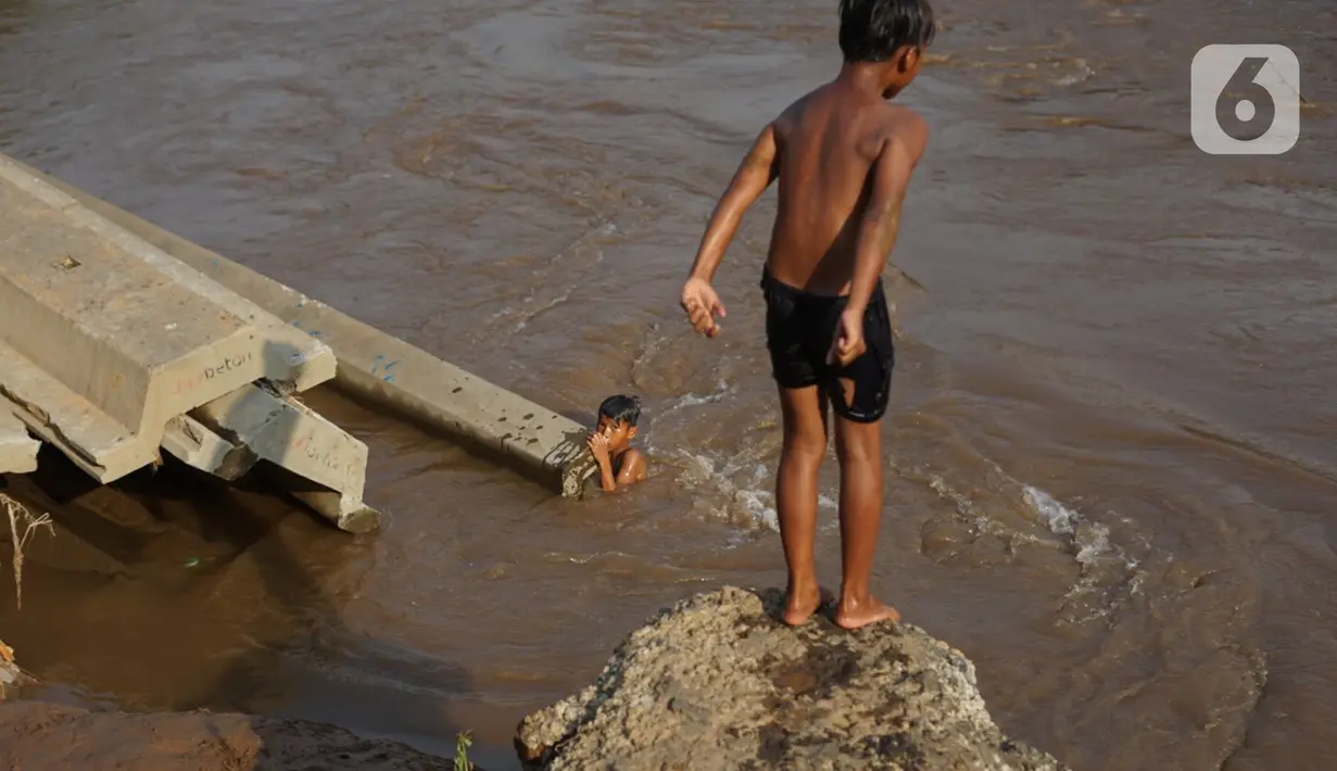 Anak-anak berenang di bantaran Sungai Ciliwung, Jakarta, Senin (5/10/2020). Derasnya aliran Sungai Ciliwung akibat hujan deras yang mengguyur Jakarta tidak menyurutkan kemauan anak-anak tersebut untuk tetap berenang, meski dapat membahayakan keselamatan mereka. (Liputan6.com/Immanuel Antonius)