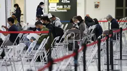 Anggota staf membantu penumpang mempersiapkan dokumen mereka selama proses karantina pencegahan virus corona mereka setelah mendarat di Bandara Internasional Narita di Narita, timur Tokyo, Jepang (2/12/2021). (AP Photo/Hiro Komae)