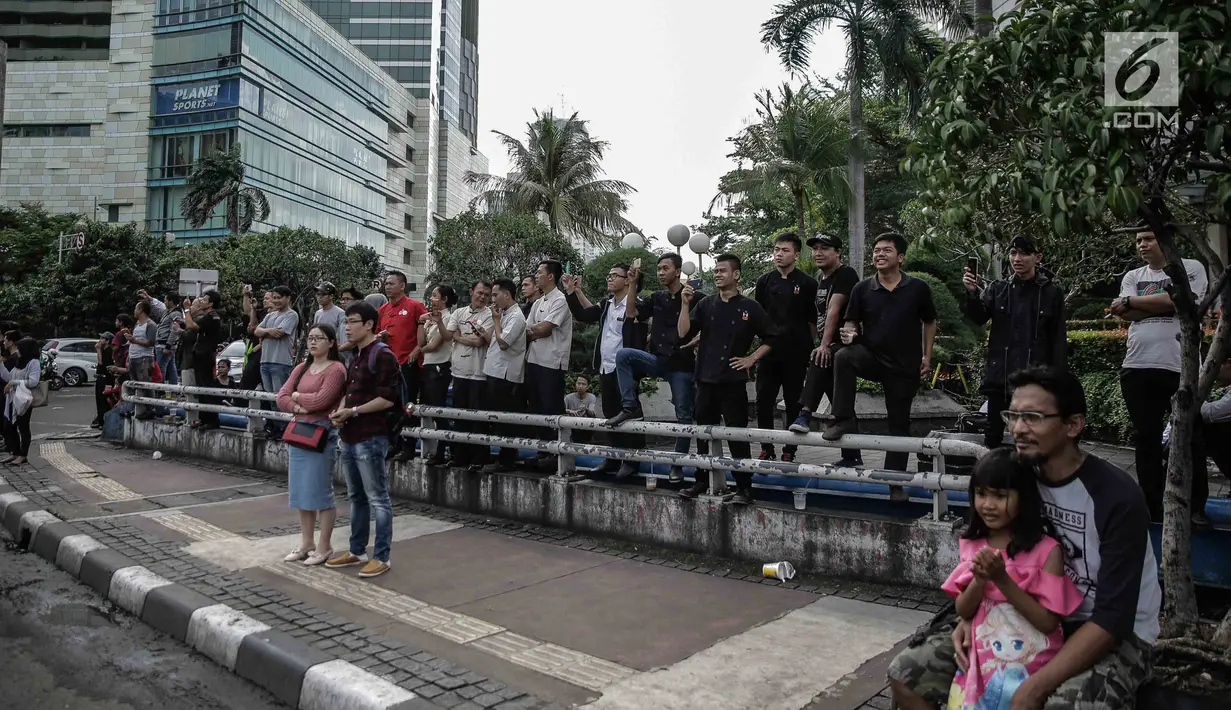 Sejumlah warga melihat konvoi kemenangan Persija Jakarta merayakan keberhasilan menjadi juara Piala Presiden 2018 di kawasan Bundaran HI, Minggu (18/2). Konvoi dimulai dari Stadion Utama Gelora Bung Karno menuju Balai Kota. (Liputan6.com/Faizal Fanani)