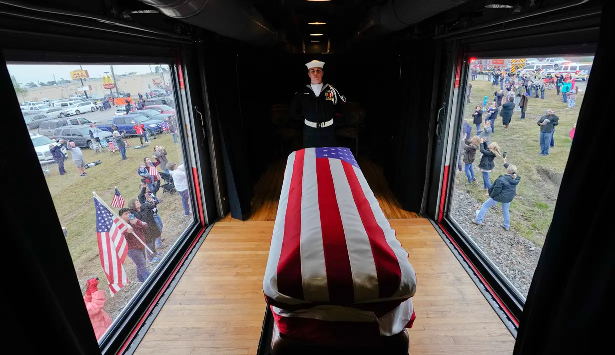 Anggota militer menjaga peti jenazah Presiden ke-41 AS George HW Bush dalam sebuah kereta saat melintasi Magnolia, Texas, Kamis (6/12). Kereta pembawa jenazah George HW Bush berangkat dari Houston menuju College Station. (AP Photo/David J. Phillip, Pool)