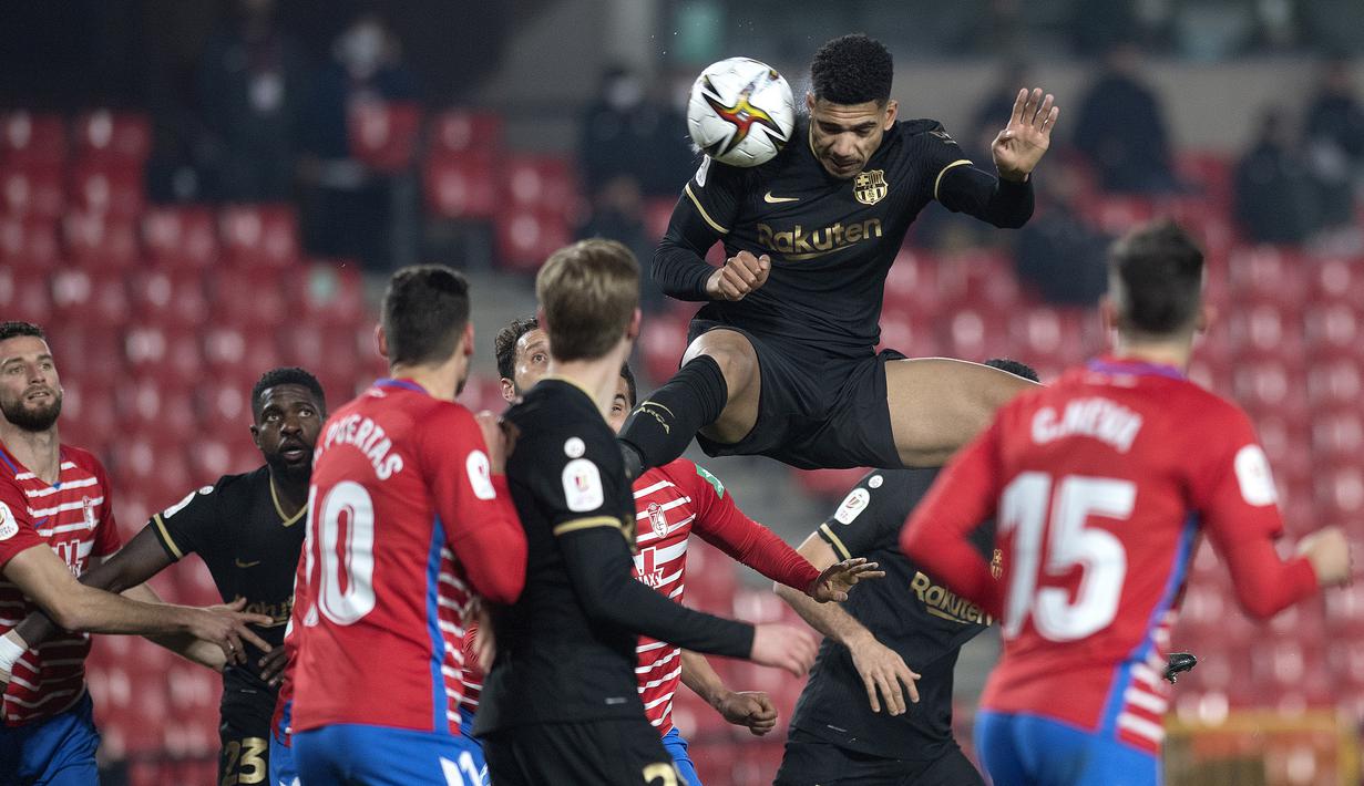 Bek Barcelona, Ronald Araujo (atas) menyundul bola dari ancaman pemain Granada dalam laga perempatfinal Copa del Rey 2020/21 di Nuevo Los Carmenes Stadium, Rabu (3/2/2021). Barcelona menang 5-3 (2-2) atas Granada melalui babak extra time. (AFP/Jorge Guerrero)