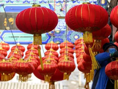 Seorang pekerja memasang lentera tradisional Tiongkok di sepanjang gang menjelang Tahun Baru Imlek di Beijing, China, 2 Februari 2021. Imlek tahun ini jatuh pada tanggal 12 Februari 2021. (NOEL CELIS/AFP)