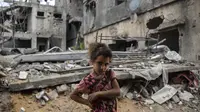 Warga Palestina Rahaf Nuseir (10) melihat saat berdiri di depan rumah keluarganya yang hancur di kota Beit Hanoun, Jalur Gaza, Jumat (21/5/2021). Israel dan Hamas telah sepakat untuk gencatan senjata setelah 11 hari pertempuran. (AP Photo/ Khalil Hamra)