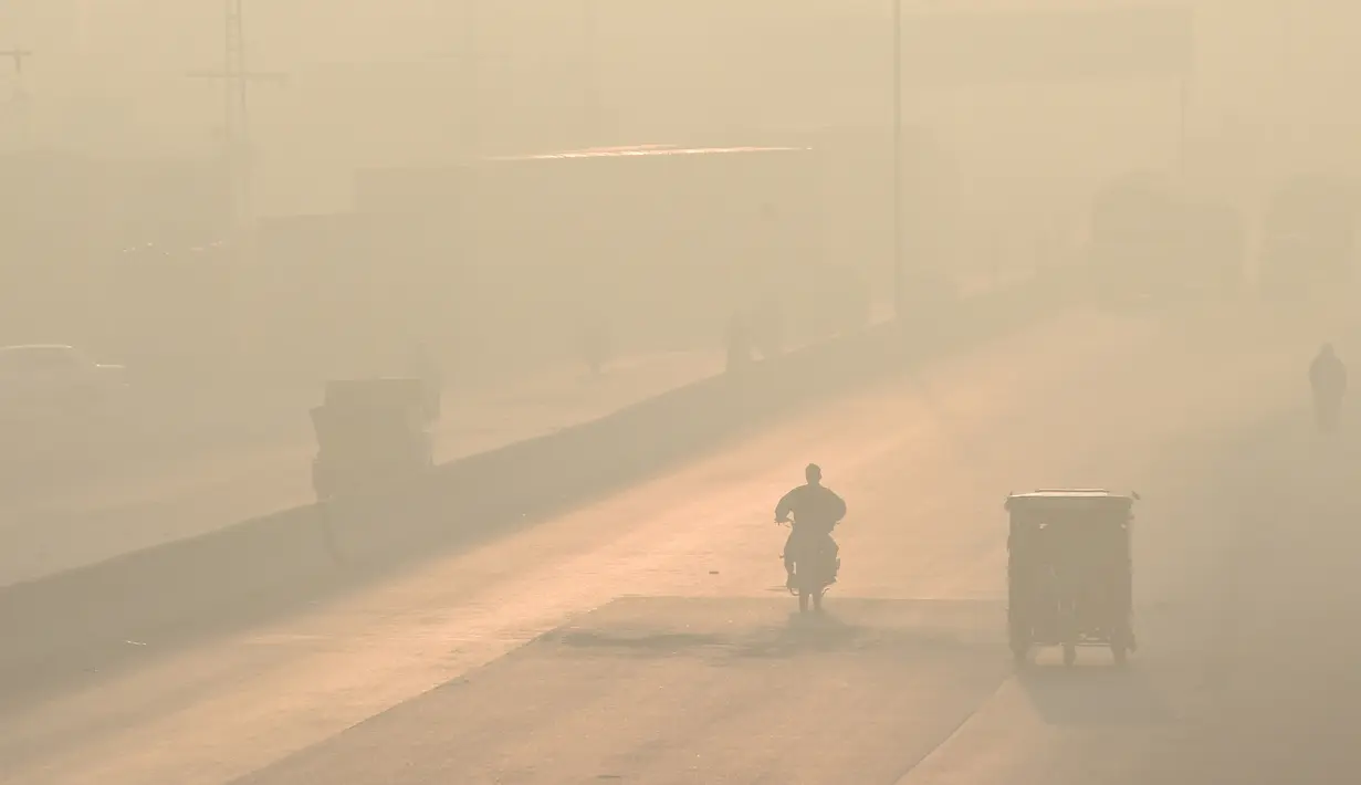 Pengendara melintas di sepanjang jalan di tengah kondisi kabut asap di Lahore, Pakistan (23/11/2021). Kondisi kabut asap yang memburuk membuat Lembaga pendidikan, kantor swasta tutup selama tiga hari seminggu di Lahore. (AFP/Arif Ali)